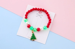 Detail view of a Christmas beaded bracelet with pearl beads and a green tree charm