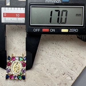 Macro shot showing 17mm size measurement of a gold Virgin Mary zircon pendant