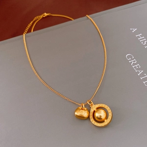 Detail of matte gold double-pendant necklace featuring a lock and geometric charm
