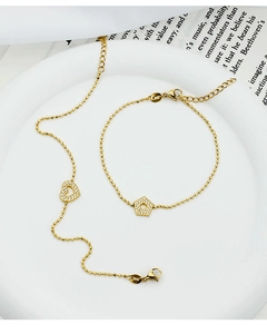 Macro detail of gold-plated heart and pentagon charms on thin bead bracelets