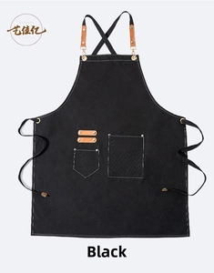 Detail of black cotton canvas apron with brown faux leather straps and metal hooks