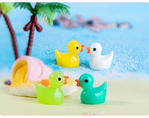 Macro shot of colorful miniature resin ducks on a sandy beach micro landscape decor