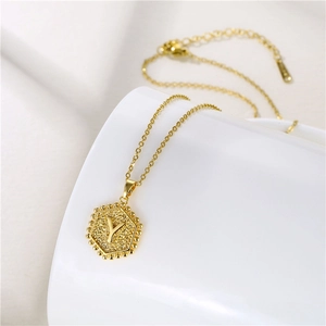 Macro detail of gold hexagon pendant with letter Y engraving on a fine chain necklace