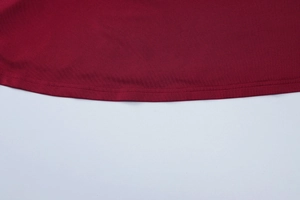 Detail view showing double-stitched hem on burgundy slim fit dress with quality knitting