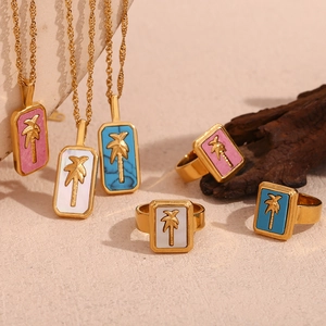 Macro detail of tropical 18K gold plated necklaces and rings with palm tree shell charms
