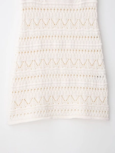 Close-up of white crochet halter mini dress showing intricate wave hollow-out knit pattern