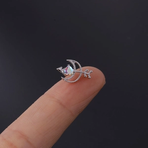 Close-up of small surgical steel moon stud earring with colorful crystal on fingertip