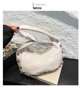 Close-up of white glossy hobo bag with silver metal rivets and knotted handle detail