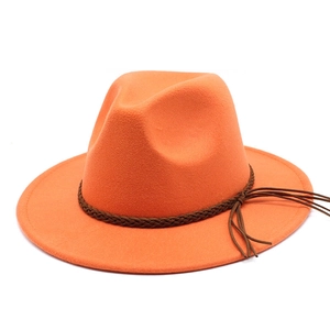 Detailed view of orange wide-brim fedora hat with woven band and leather tassels