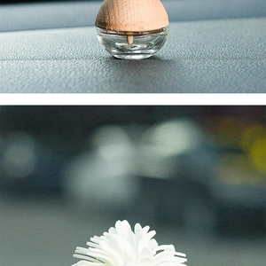 Macro shot of glass aromatherapy bottle with wood lid and floral ceramic diffuser