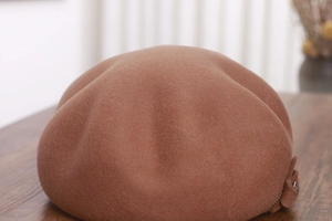 Detail of wool octagonal hat featuring side bow tie and decorative metal zipper