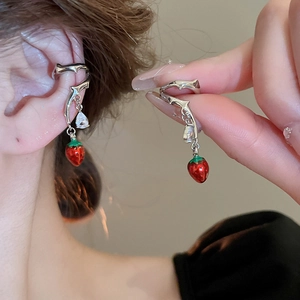 Detailed shot of a red strawberry pendant and zircon drop on a silver ear bone clip