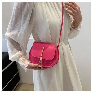Close-up of rose pink saddle bag featuring gold metal hardware and elegant fringe detail