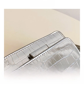 Detail shot of silver faux leather shoulder bag with embossed crocodile texture and stitching