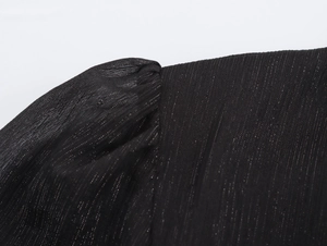 Détail du tissu en mousseline noire avec texture rayée fine et reflets scintillants