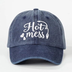 Detailed view of Hot Mess embroidery and heart shapes on washed blue denim baseball cap