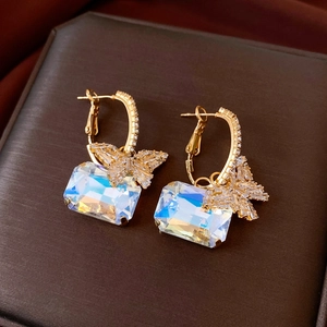 Macro shot of gold butterfly pendant earrings with iridescent crystals on a jewelry box