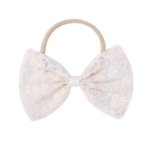 Detailed view of exquisite white embroidery lace bow on a soft elastic baby headband