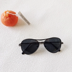 Flat lay of kids aviator sunglasses with black metal frame and dark lenses on white background
