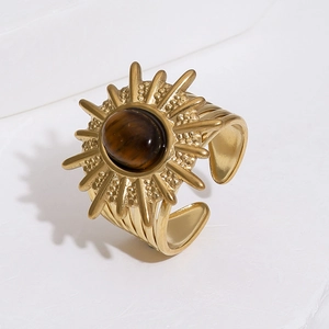 Detail of sun-shaped gold ring featuring a polished oval tiger eye stone center