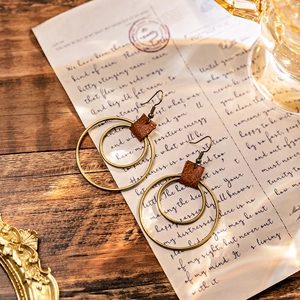 Bohemian geometric double circle drop earrings with brown leather accents on vintage background
