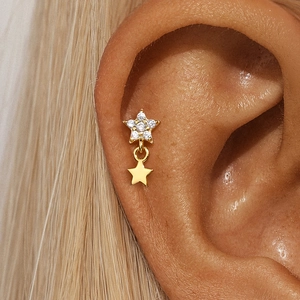 Detailed close-up of golden S925 silver star earring with sparkling stones on model's ear