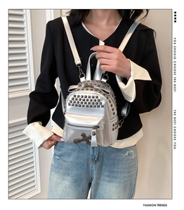 Detail of silver mini PU leather backpack with punk rivets and cross charms on model