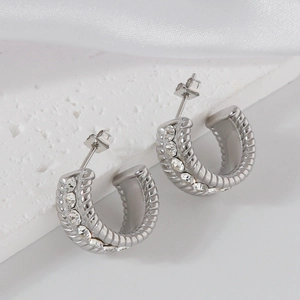 Silver-plated twisted hoop earrings with sparkling cubic zirconia on stone and satin background