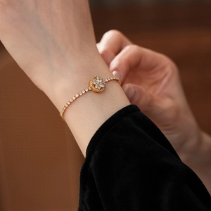 Detail of adjustable gold-tone clover bracelet with micro-paxed zircon on wrist