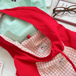 Detail of red tote bag with red and white checkered lining and inner pocket