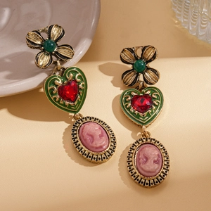 Close-up of vintage drop earrings featuring floral hearts and cameo portrait charms