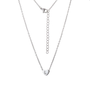 Gros plan détaillé d'un pendentif cœur en argent avec la lettre L gravée sur une fine chaîne