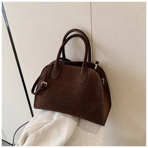 Detail of dark brown suede tote bag featuring adjustable gold hardware and matte finish