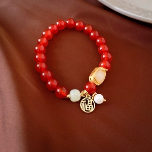 Détail de perles d'agate rouge avec pendentif doré Fu et breloque en jade sur satin