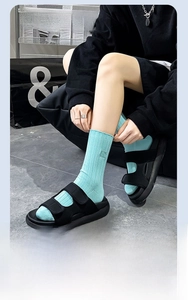 Détail de chaussettes vert menthe à côtes avec écusson brodé et sandales noires