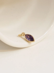 Macro shot of marquise-cut purple birthstone pendant with 18K gold plated bezel setting