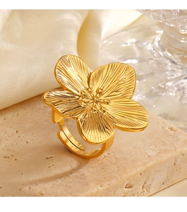 Dettaglio dell'anello a fiore placcato oro 18K con trama fine su base in marmo beige