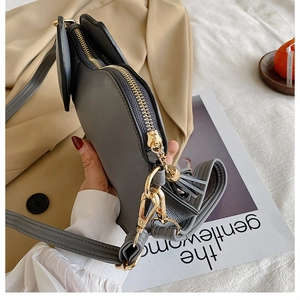 Detail of grey leather crossbody bag with golden zipper and fringe tassel chain strap