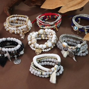 Detail of bohemian multilayer beaded bracelets with tassels and charms on a rustic background