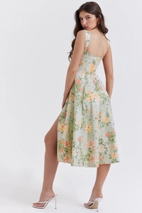 Detail showing high-slit floral dress in light green with vibrant orange blossom patterns