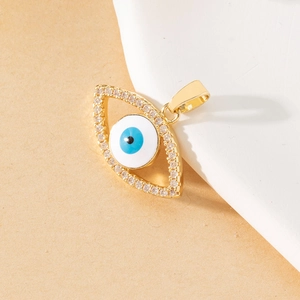 Detailed macro view of a gold Evil Eye pendant with blue pupil and crystal bezel