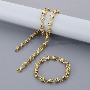 Parure collier et bracelet en acier titane doré avec maillons entrelacés sur socle