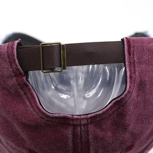 Detail of vintage washed baseball cap featuring brown leather strap and bronze buckle