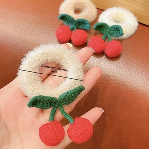 Detail shot of crochet cherry plush scrunchie with 6cm diameter measurement guide