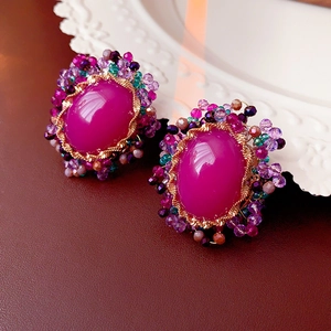 Macro shot of vintage oval purple gemstone earrings with colorful beadwork and gold wire