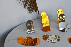 Detailed view of orange and silver acrylic mirror jewelry display stands with dry plants