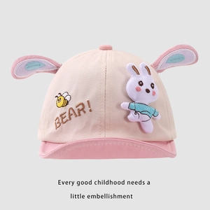 Detailaufnahme einer rosa Babykappe mit Plüschhasenohren und Bienenstickerei auf dem Schirm