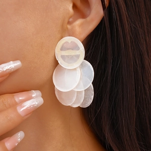 Macro detail of layered circular faux shell earrings with glossy milky white finish