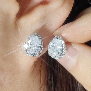 Close-up of elegant pear-cut teardrop earrings with halo diamond setting on ear
