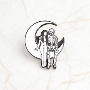 Detail of gothic enamel pin with moon, skeleton and female figure on marble background